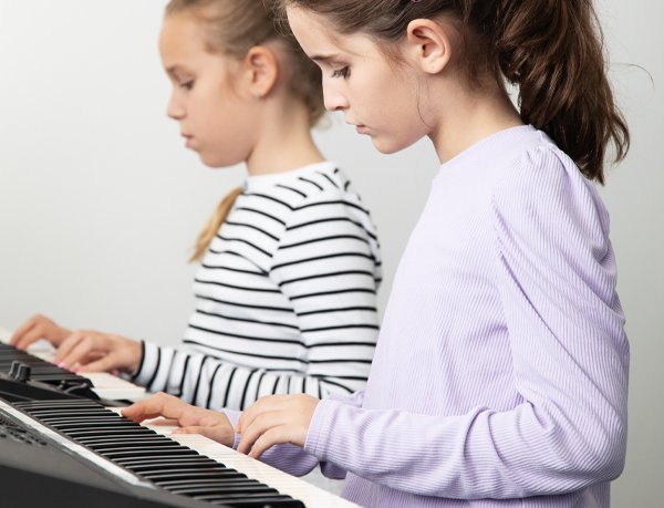 Mokinės groja klavišiniais instrumentais